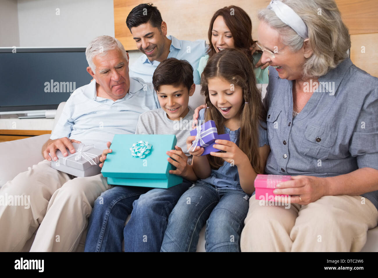 Großfamilie auf Sofa mit Geschenk-Boxen im Wohnzimmer sitzen Stockfoto