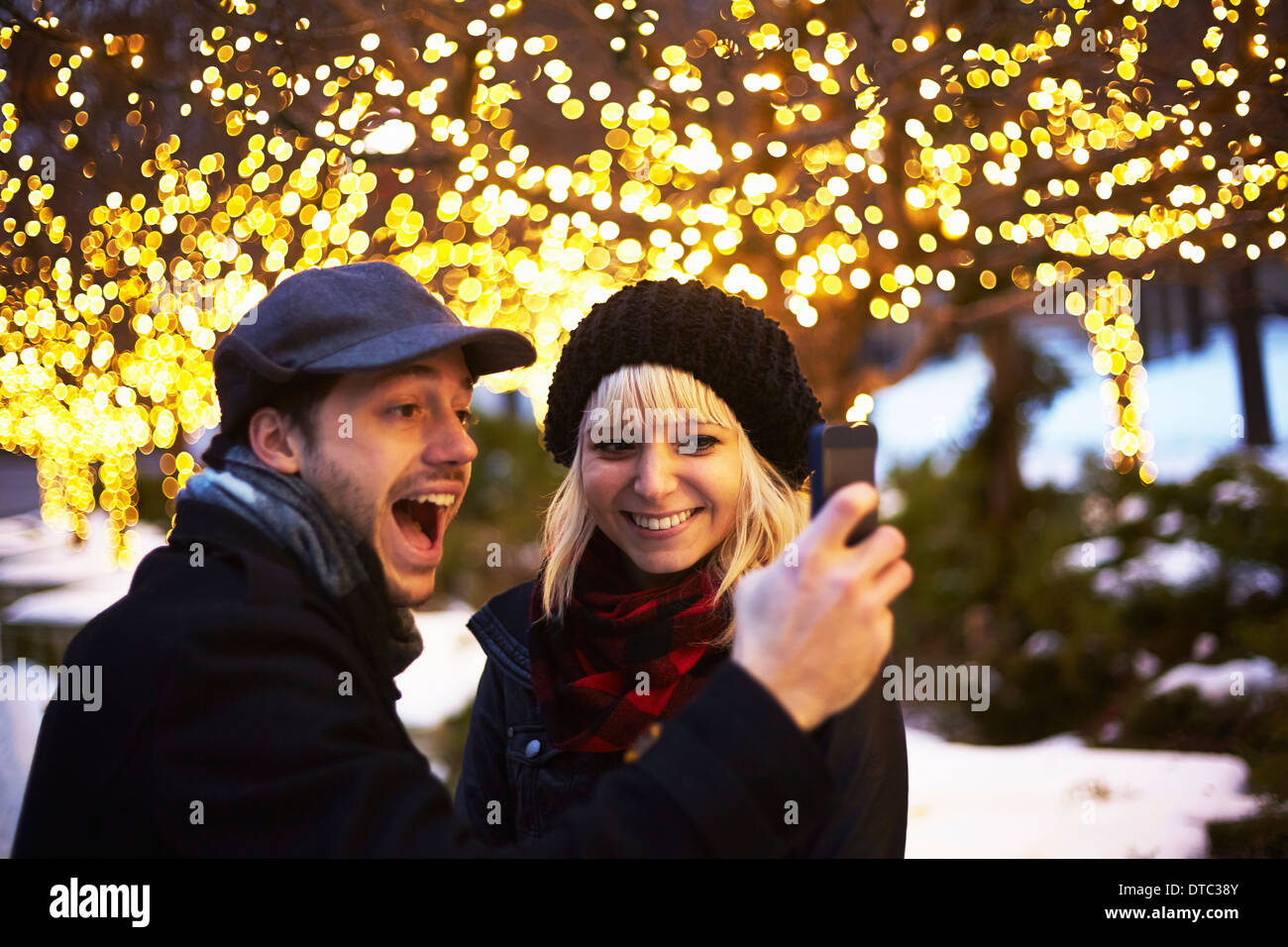 Junges Paar unter Selbstbildnis mit outdoor Weihnachtslichter Stockfoto