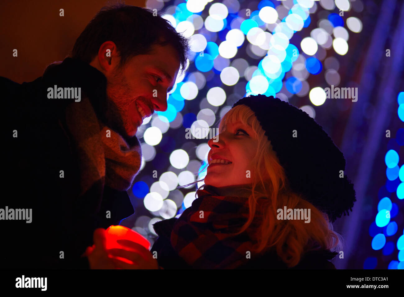 Junges Paar halten Kerze vor Weihnachtslichter der Stadt Stockfoto