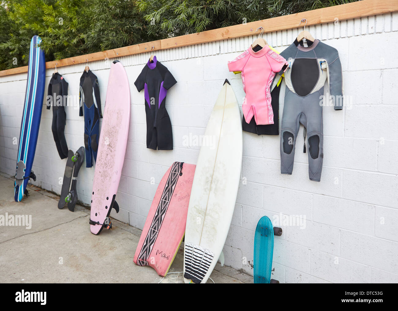 Surfboards und Skateboards lehnte sich gegen die Wand und Neoprenanzüge hängen Stockfoto