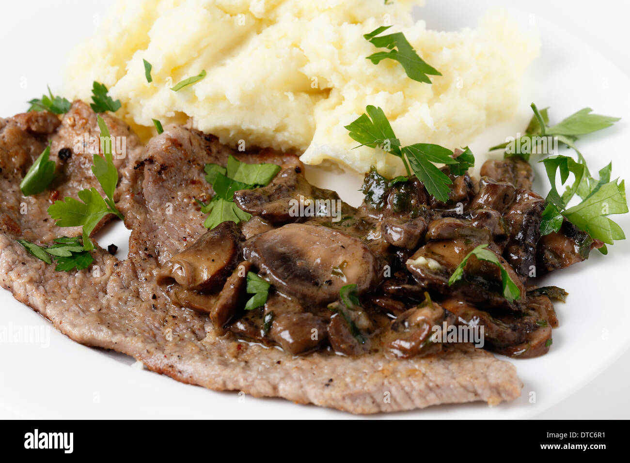 Fried und gepfefferten Kalbsschnitzel serviert mit Kartoffelpüree und eine cremige sautierten Pilzsauce Stockfoto