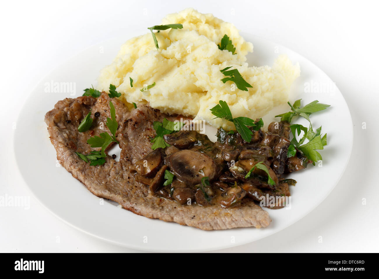 Fried und gepfefferten Kalbsschnitzel serviert mit Kartoffelpüree und eine cremige sautierten Pilzsauce Stockfoto