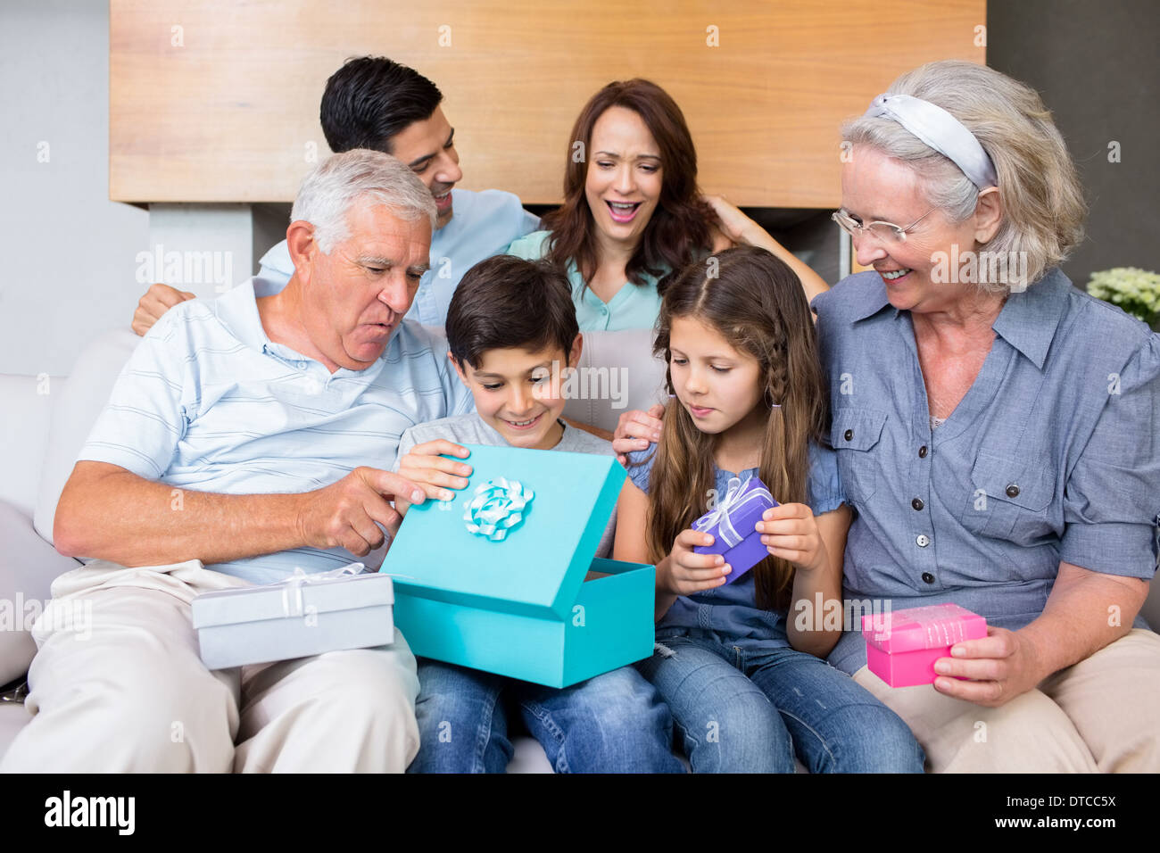 Großfamilie auf Sofa mit Geschenk-Boxen im Wohnzimmer sitzen Stockfoto