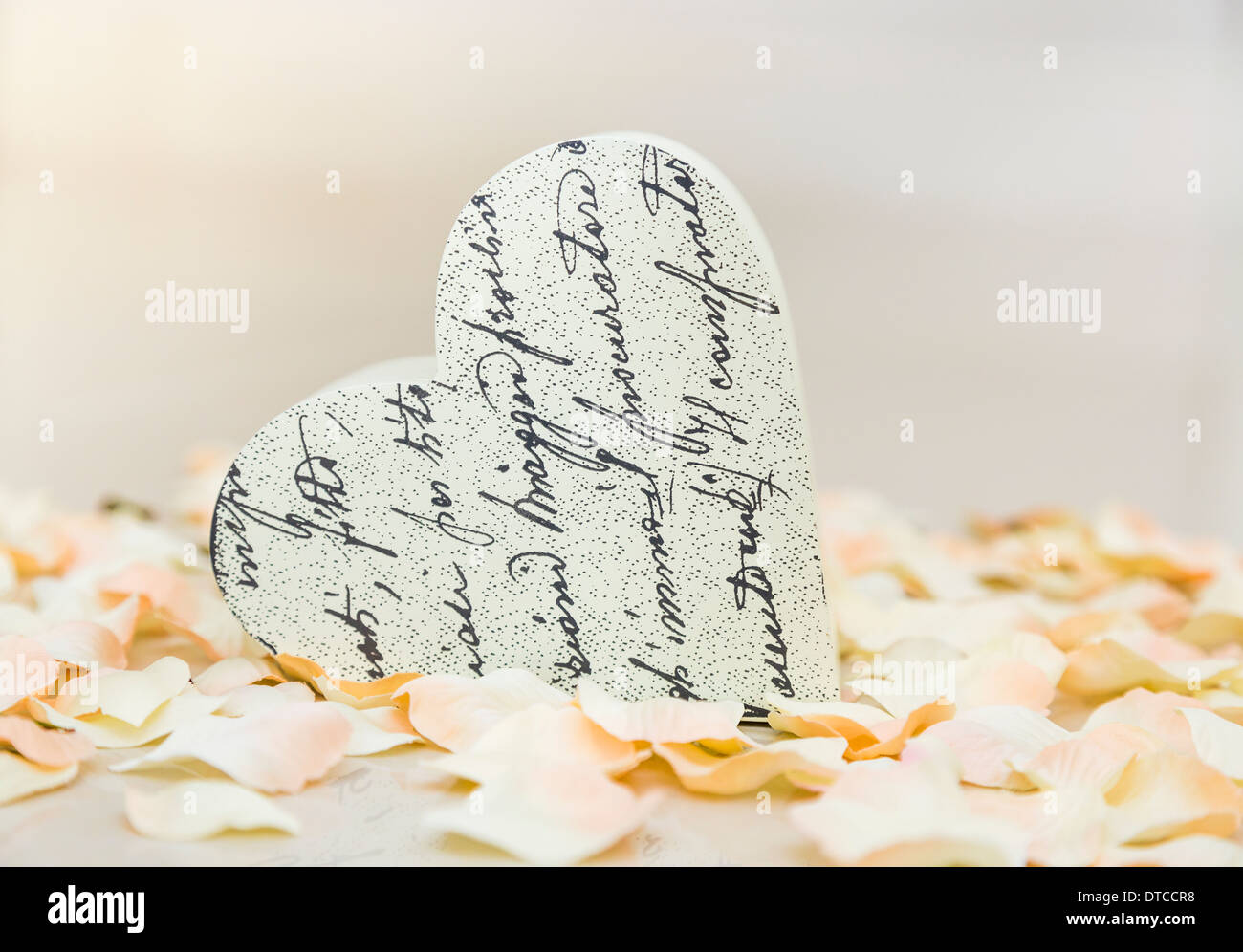 Herzförmiges Ornament auf einem Bett aus künstlichen rosa und weiße Rosenblätter Stockfoto