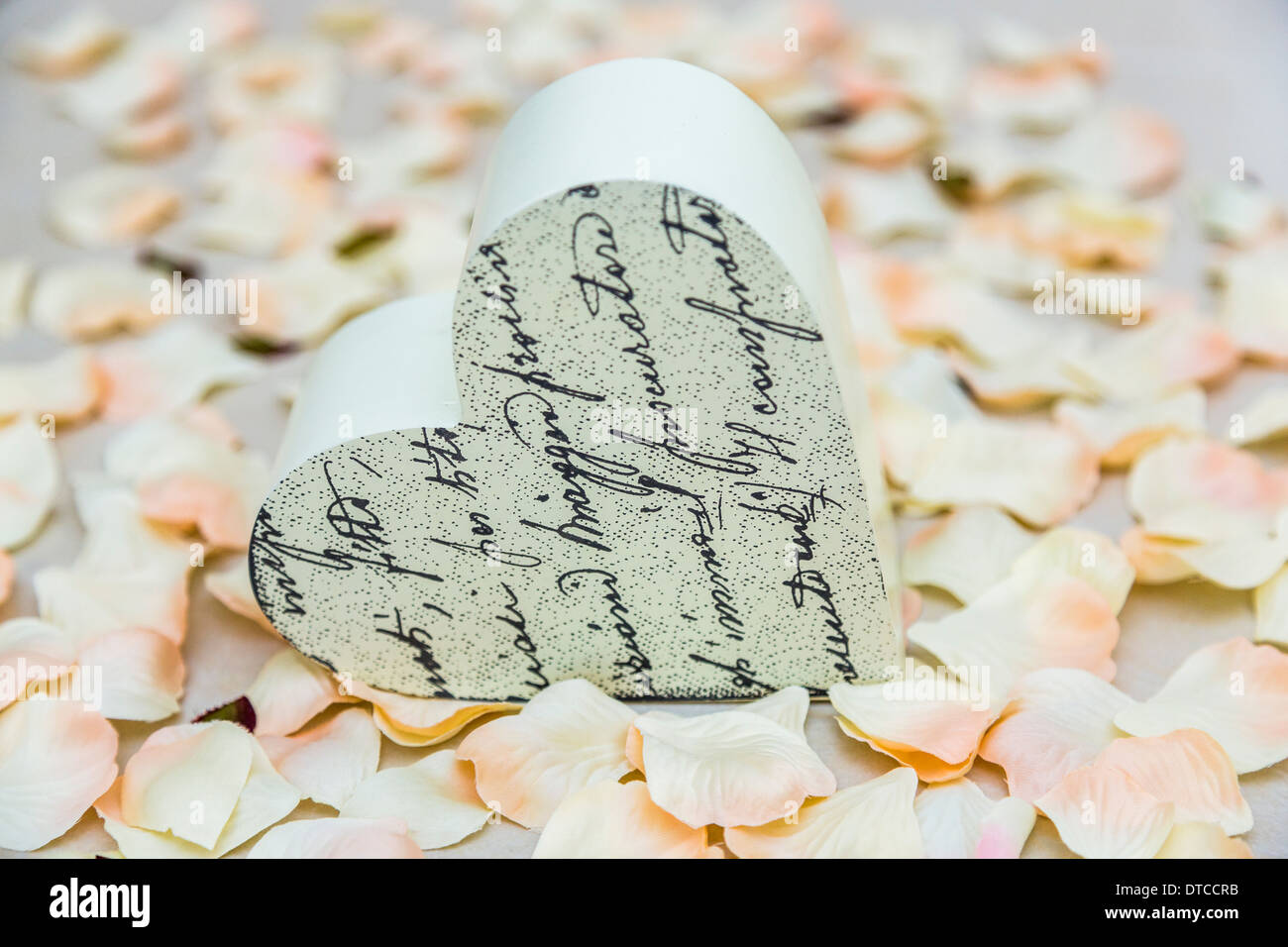 Herzförmiges Ornament auf einem Bett aus künstlichen rosa und weiße Rosenblätter Stockfoto