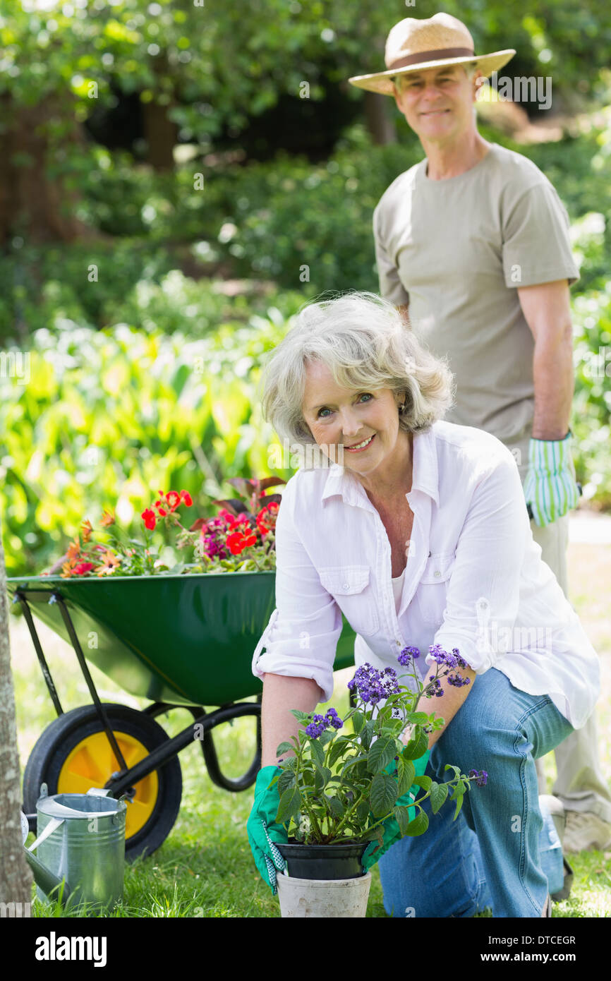 Reife Frau mit Mann im Hintergrund bei der Gartenarbeit beschäftigt. Stockfoto