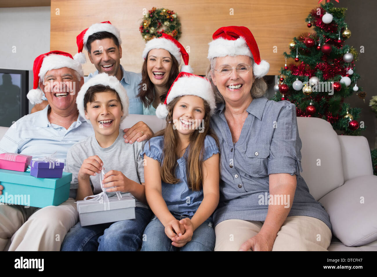 Großfamilie in Weihnachtsmützen mit Geschenk-Boxen im Wohnzimmer Stockfoto