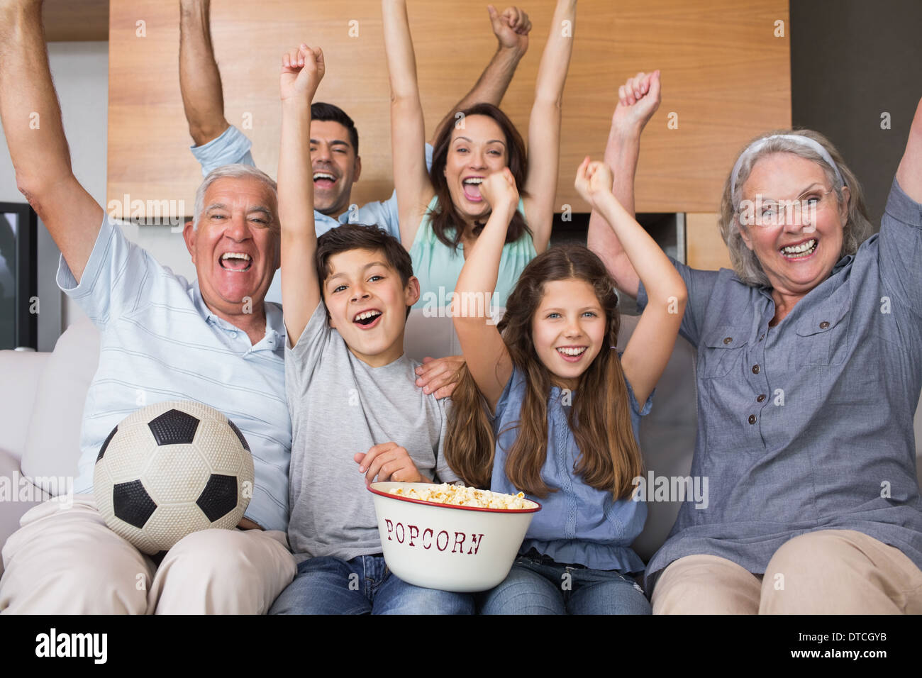 Porträt der glückliche Familie vor dem Fernseher im Wohnzimmer Stockfoto