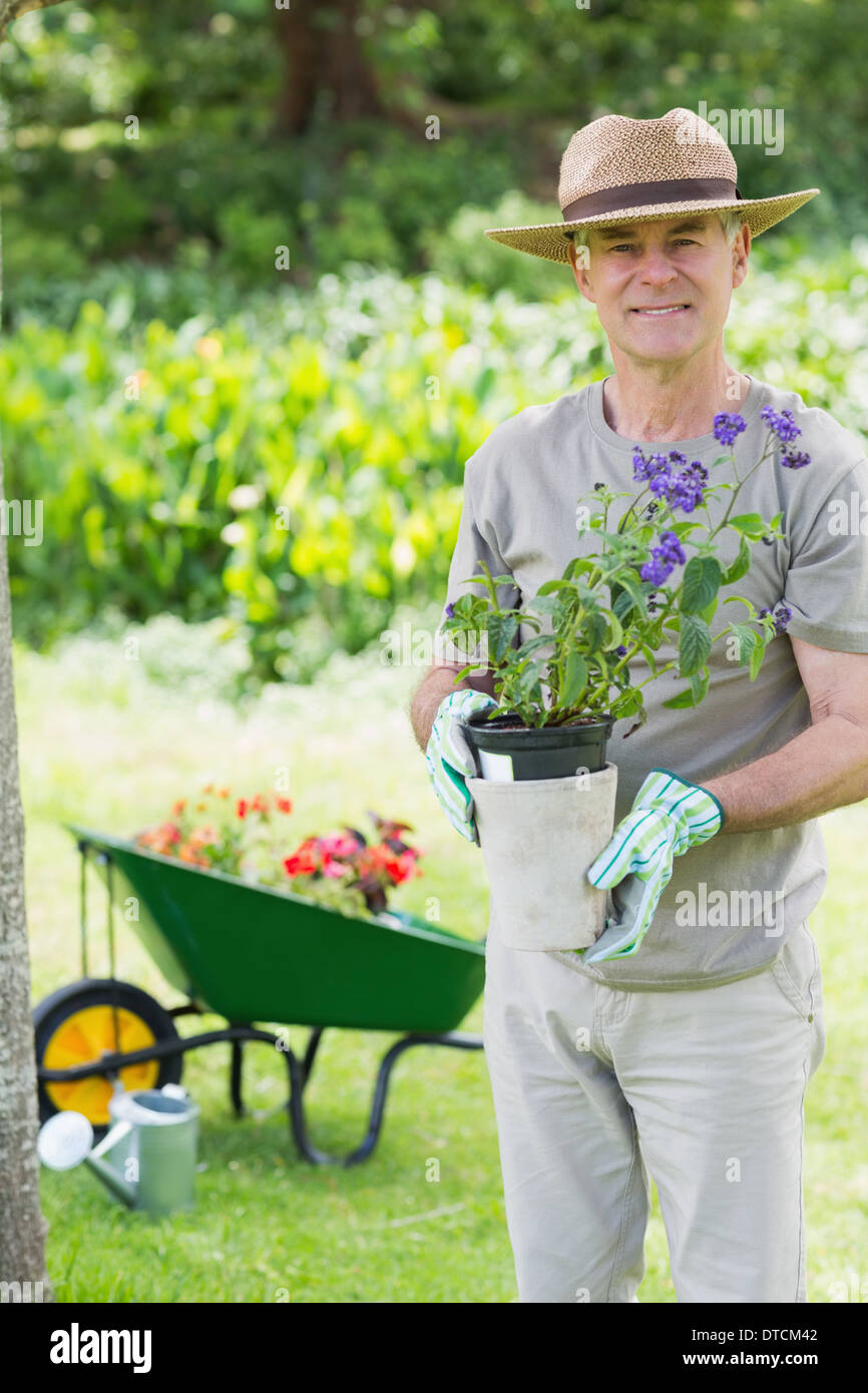 Mann hält lächelnd Topfpflanze im Garten Stockfoto