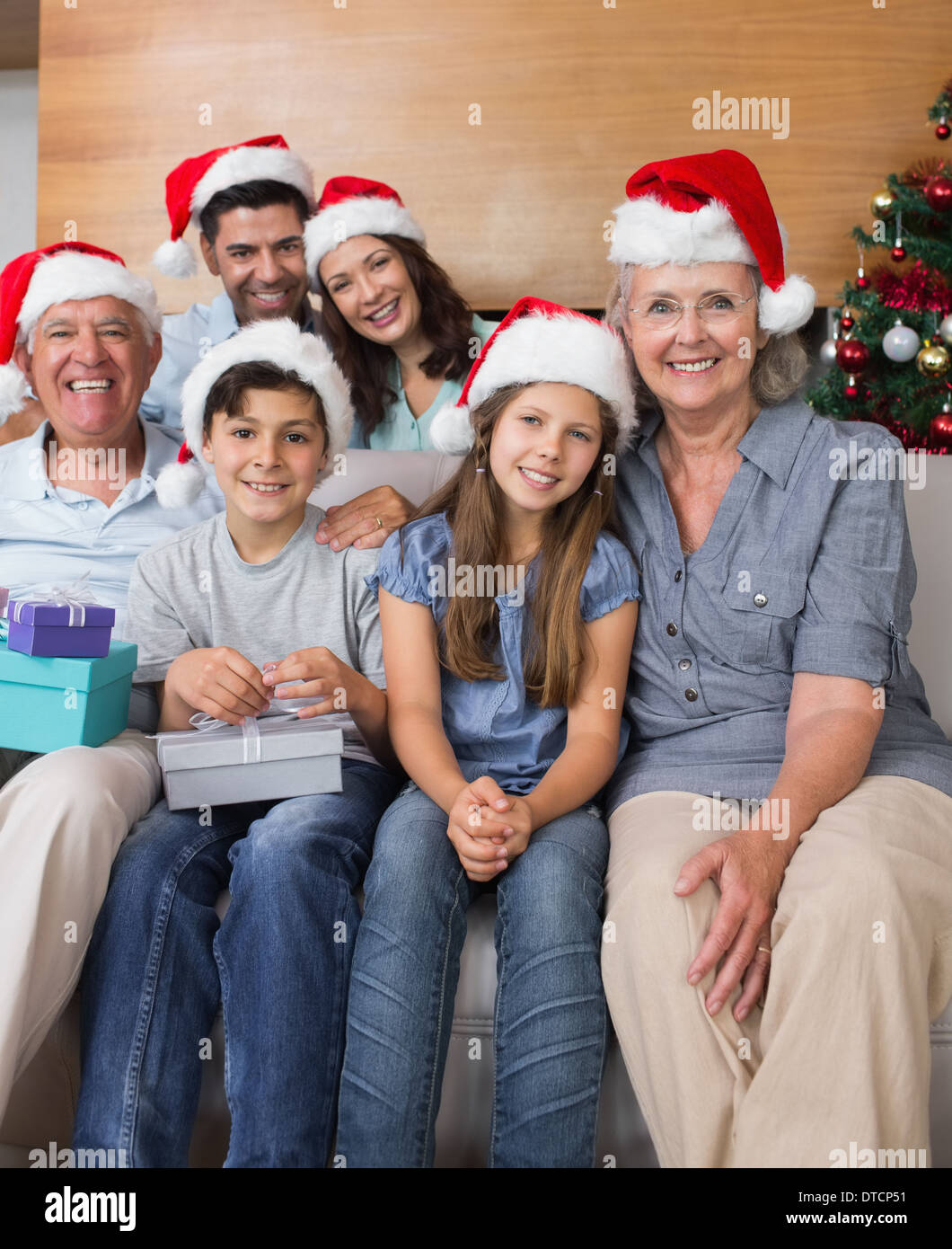 Großfamilie in Weihnachtsmützen mit Geschenk-Boxen im Wohnzimmer Stockfoto