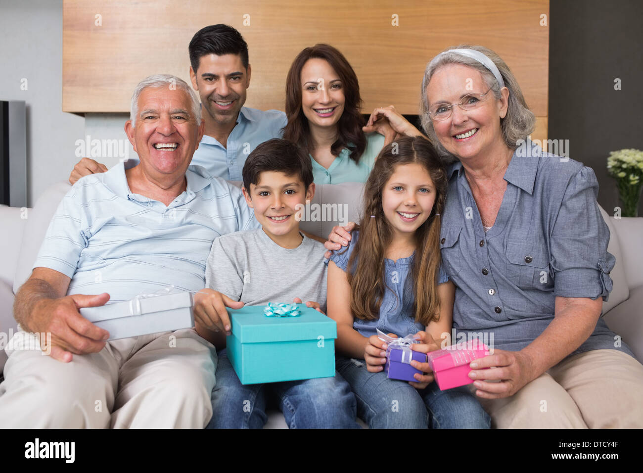 Großfamilie auf Sofa mit Geschenk-Boxen im Wohnzimmer Stockfoto