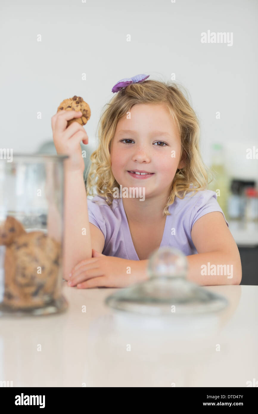 Niedliche Mädchen halten Cookie am Schalter Stockfoto