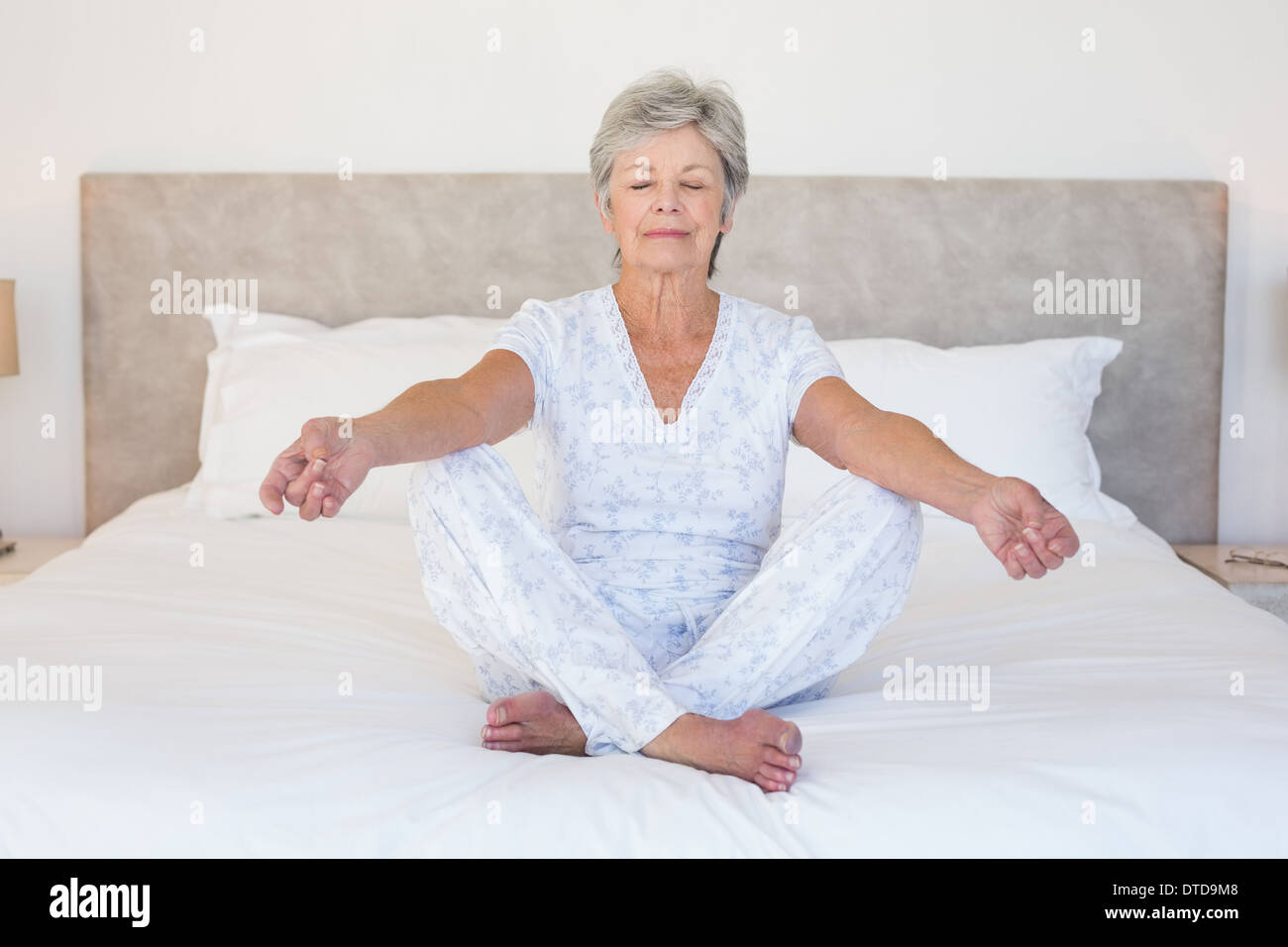Ältere Frau im Bett zu meditieren Stockfoto