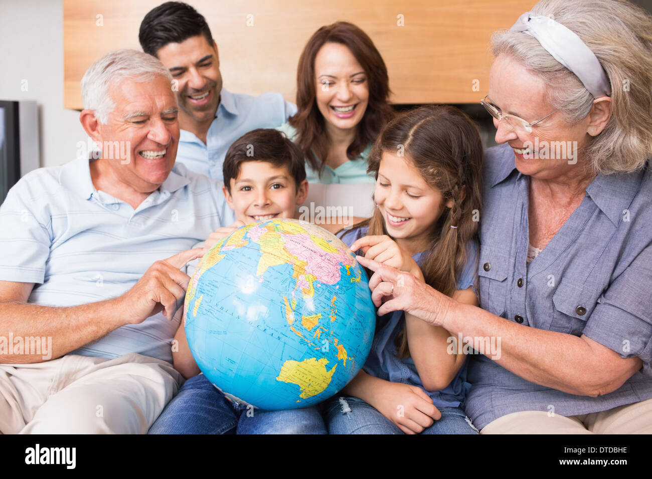 Großfamilie auf Sofa mit Globus im Wohnzimmer sitzen Stockfoto