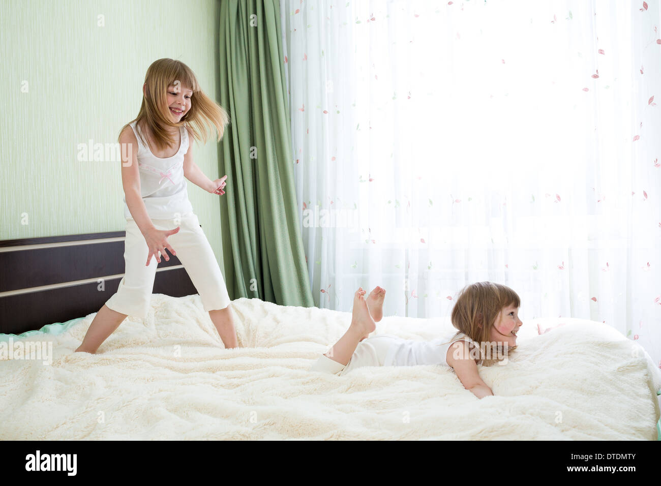 Zwei Schwestern spielen auf Bett zusammen Stockfoto