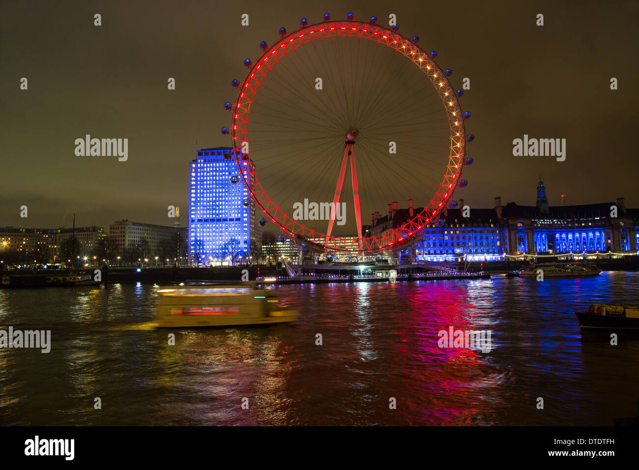 London Eye beleuchtet in der Nacht über den Fluss Themse Stockfoto