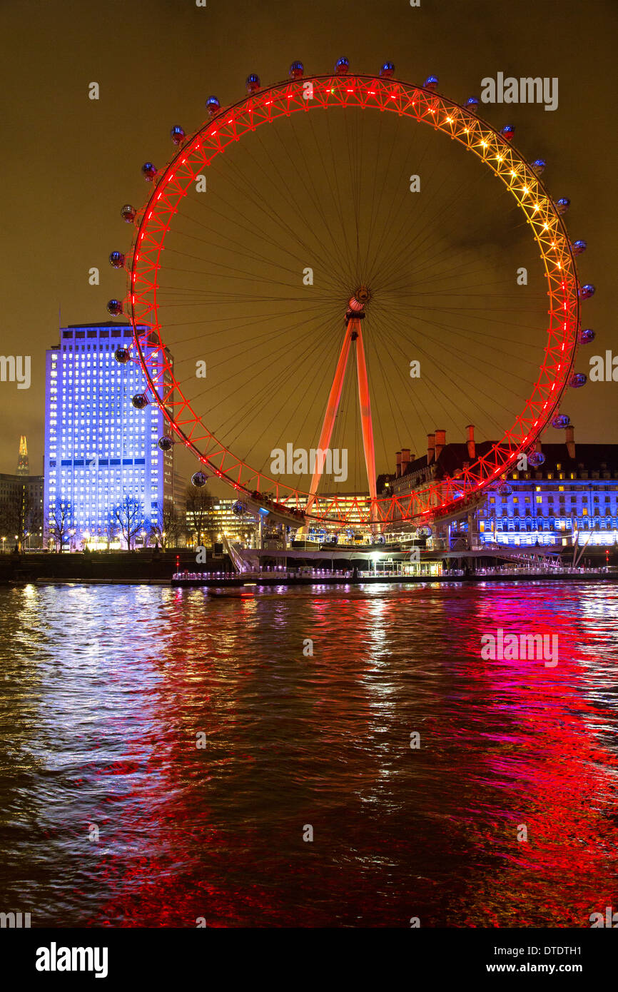 London Eye beleuchtet in der Nacht über den Fluss Themse Stockfoto