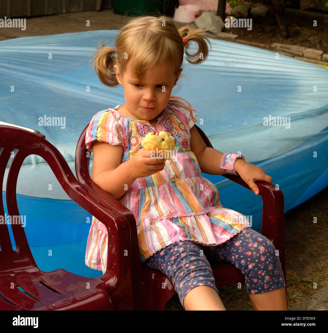 Zwei-jährigen Mädchen essen einen Apfel in der Gartenstuhl Stockfoto