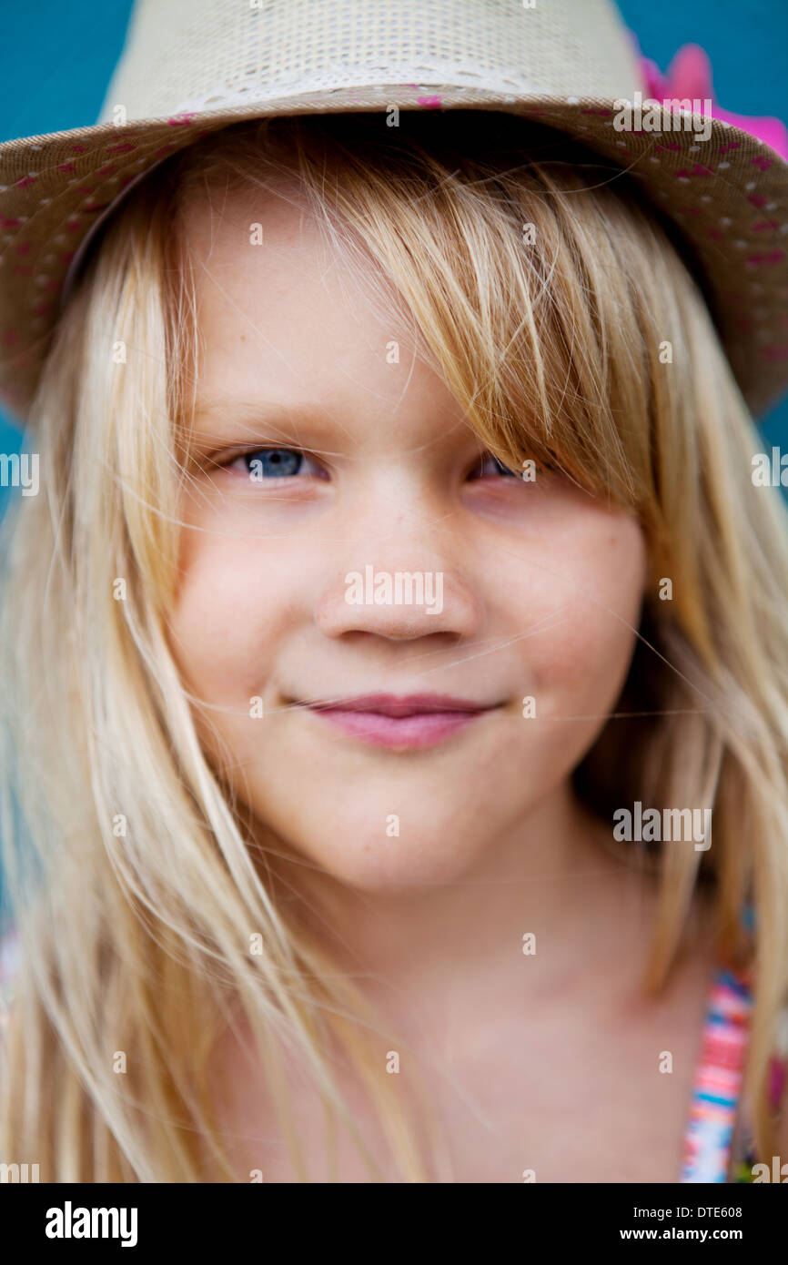 Nahaufnahme des Gesichts süß lächelnden jungen Mädchens mit stylischen Hut außerhalb Hintergrund blaue Wand Stockfoto