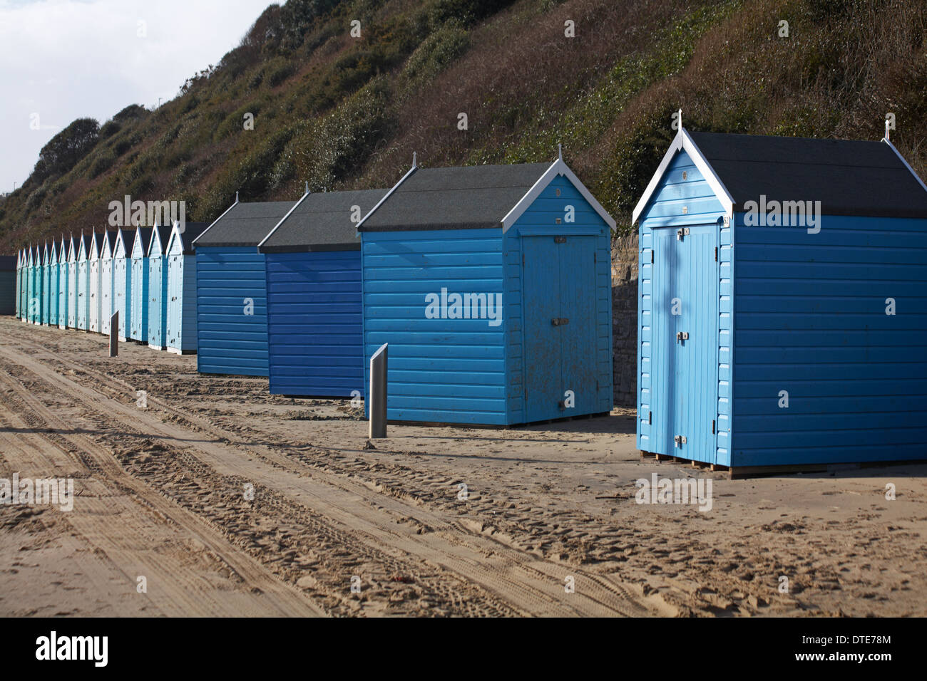 Die blauen Strandhütten blieben nach den letzten Stürmen in die falsche Richtung und waren aus der Reihe. Das Wetter war schlecht in Bournemouth, Dorset UK im Februar Stockfoto