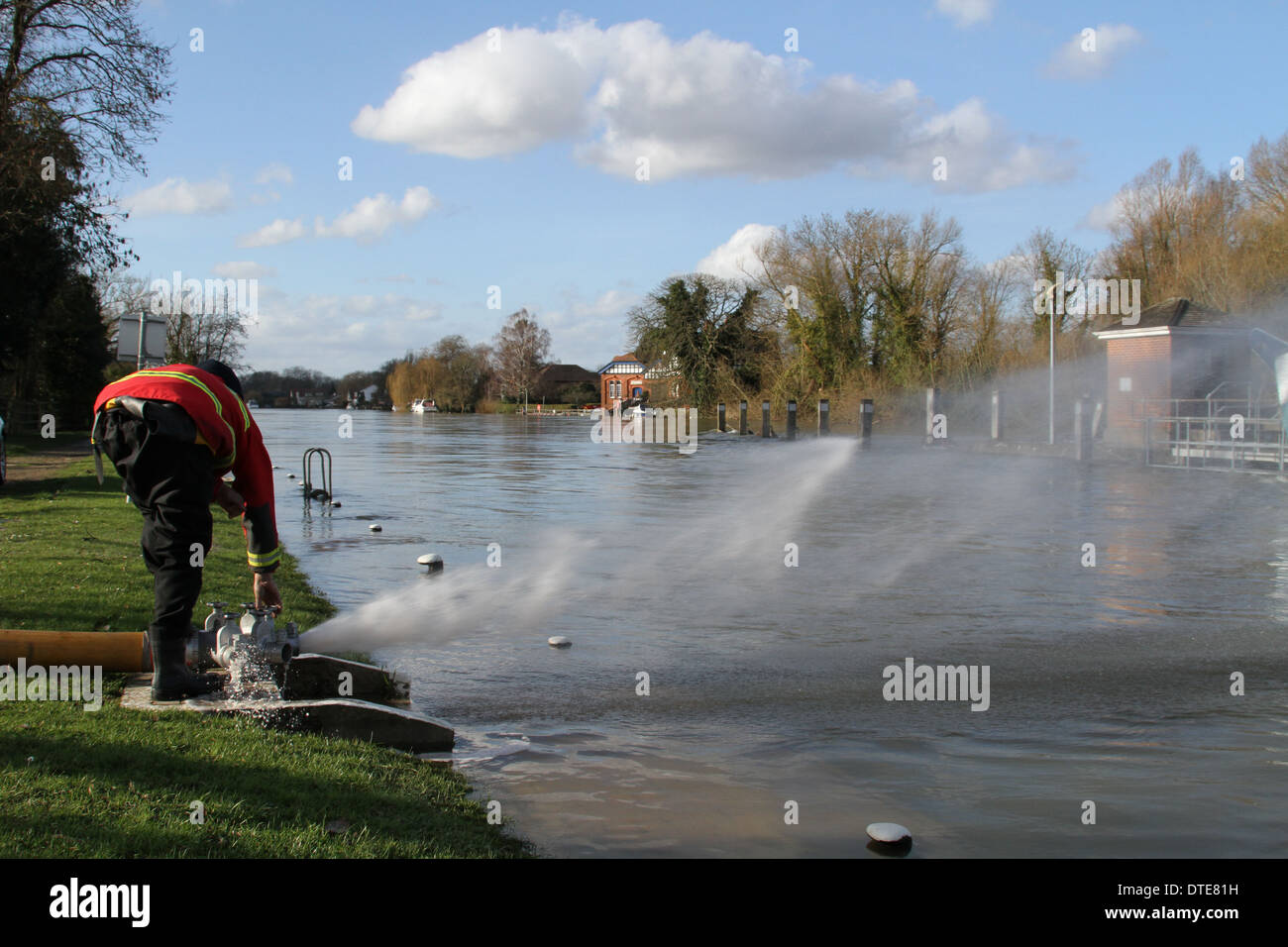 Feuerwehrmann inspiziert einen Schlauch zur Pumpe, Hochwasser von Runnymede in der Themse bei Bell Wier Lock gelegt. Stockfoto