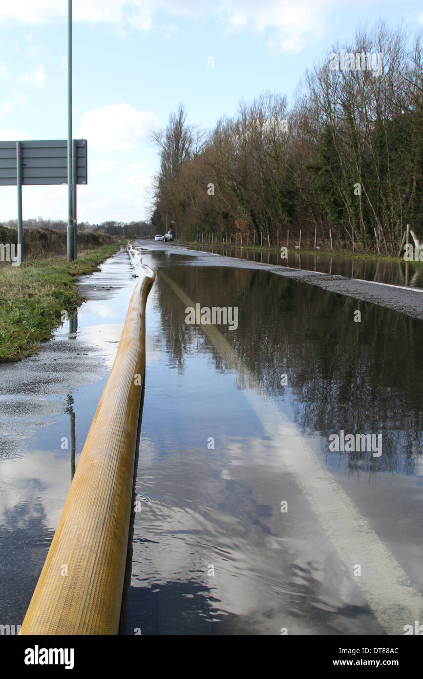 Ein Rohr gelegt durch die Feuerwehr trägt Hochwasser aus dem A308 in Egham, Surrey Stockfoto