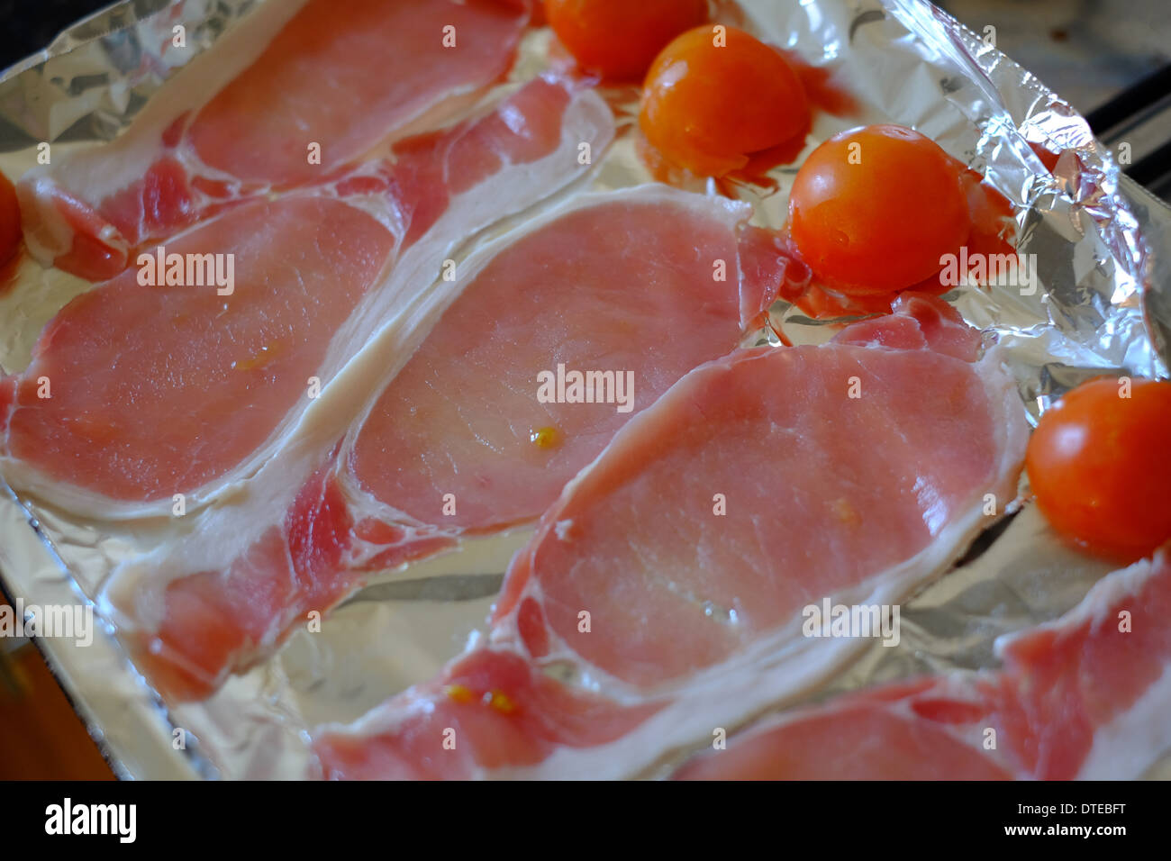 Rohem Speck und Tomaten auf einem Backblech Stockfoto