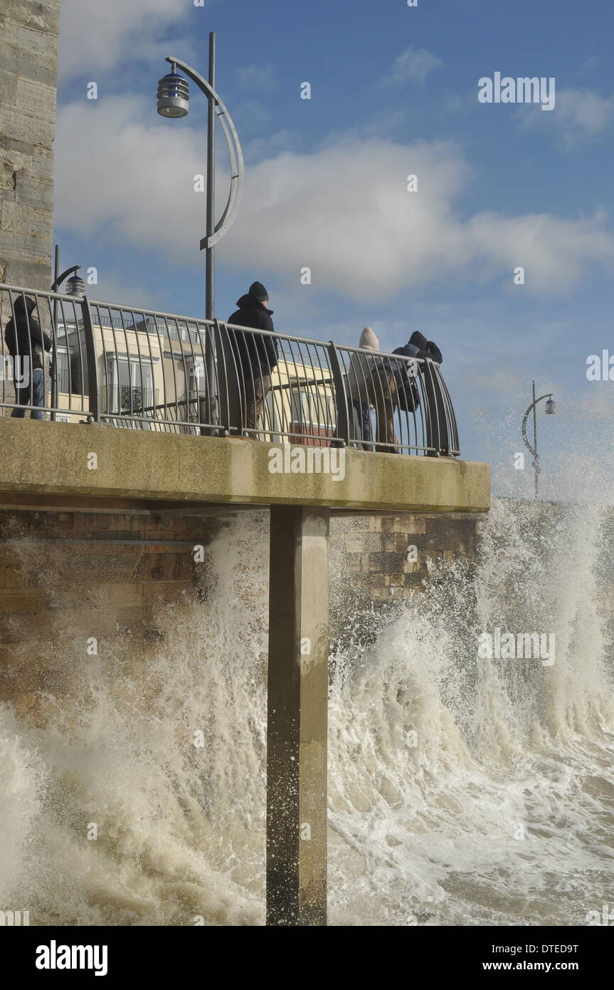 Portsmouth. UK, 15. Februar 2014 1130 bin, die Südküste Englands weiterhin die Auswirkungen der Winterstürme zu spüren. Brechenden Wellen bei Flut mit Southsea Kirmes im Hintergrund © Paul Gordon/Alamy Live News Stockfoto