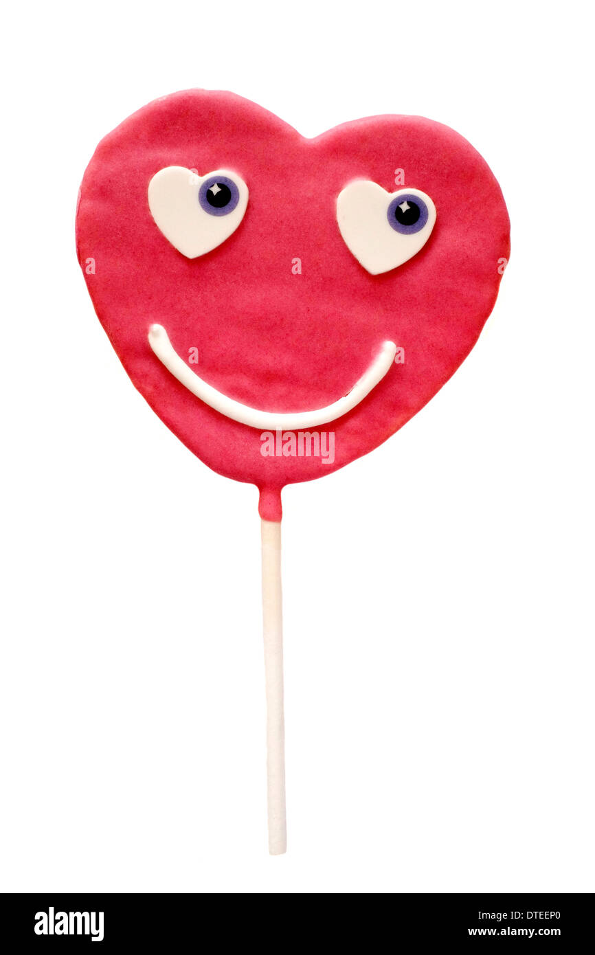 Liebe Keks mit rosa Zuckerguss und Smiley Gesicht auf einem Stick in Herzform Stockfoto