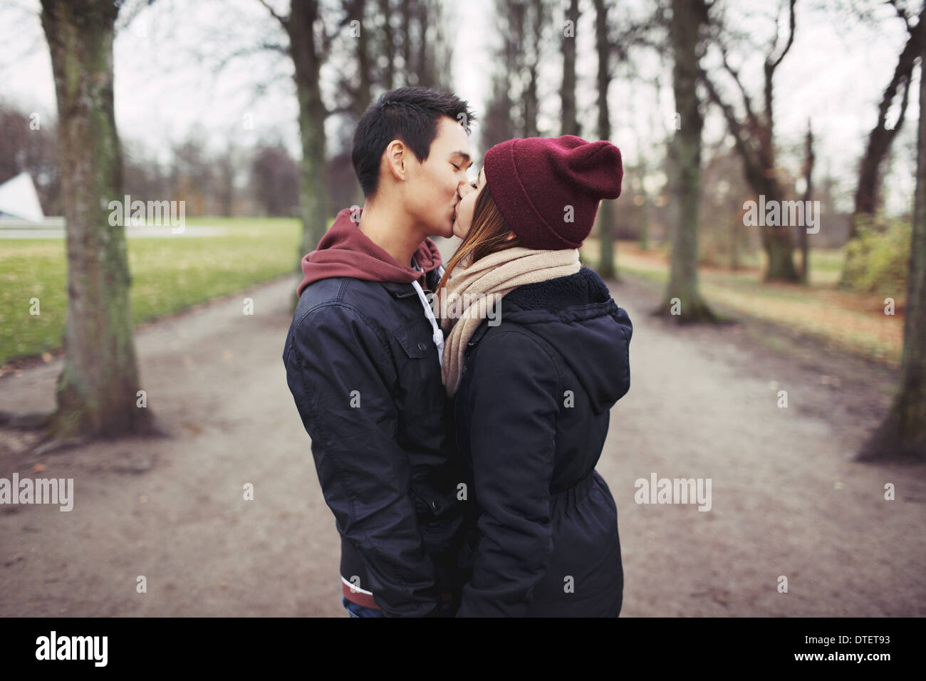 Junges Liebespaar küssen im Freien im Park. Gemischte Rassen Mann und Frau. Teenager Liebe. Stockfoto