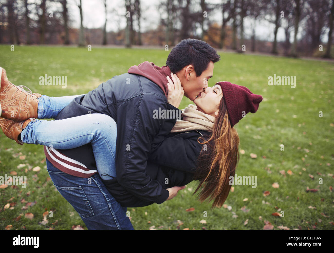 Attraktiver junger Mann mit seiner hübschen Freundin und küssen. Mischlinge-paar in der Liebe im Freien im Park. Stockfoto