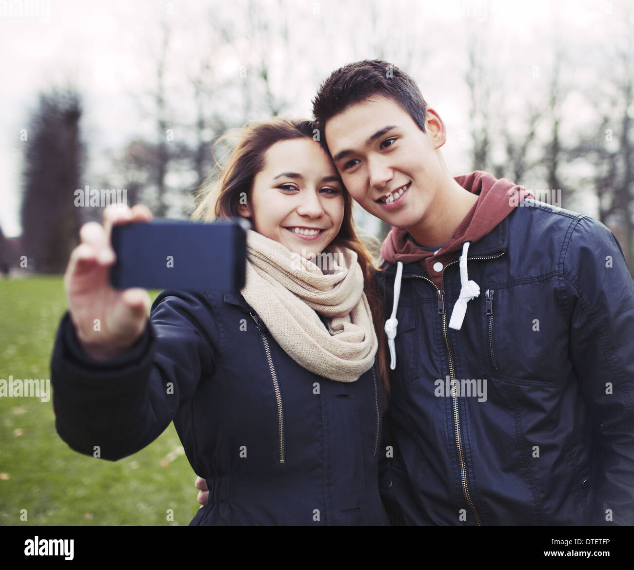 Süße junge Paar suchen glücklich während des Fotografierens mit einem Smartphone im Park. Gemischte Rassen Teenager-Jungen und Mädchen in der Liebe Stockfoto