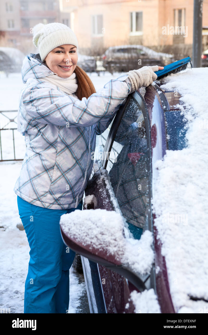 Glückliche Frau Motorhaube im Winter Schnee entfernen Stockfoto