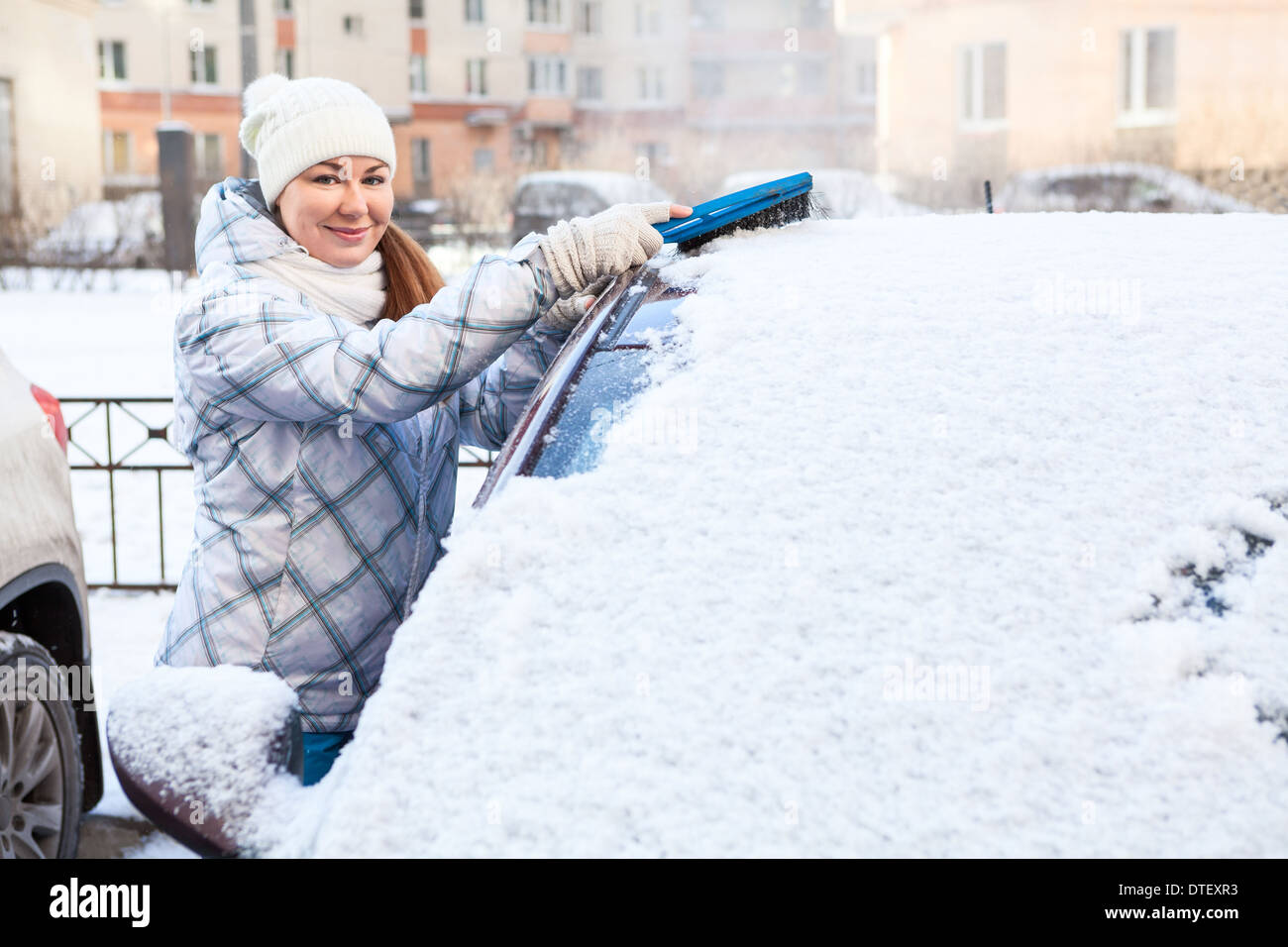 Attraktive Frau Bürsten Schnee von der Windschutzscheibe Stockfoto