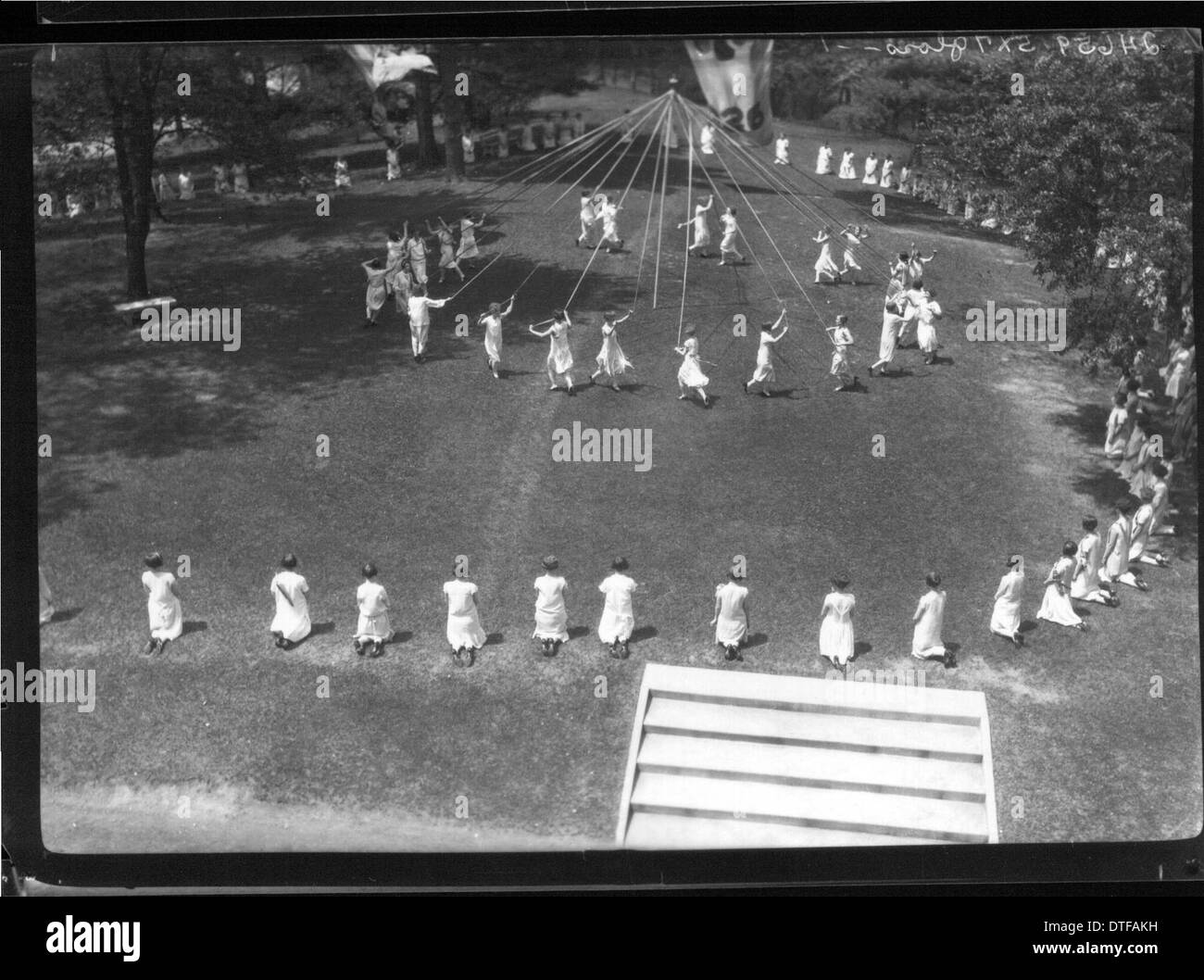 Dieses Foto aus dem Jahr 1926 zeigt eine Feier am Western College in Oxford, Ohio, mit Maypole-Tänzern und Open-Air-Theaterproduktionen. Die Veranstaltung, die Teil der Tradition des Colleges ist, hebt die Rolle der Ausbildung und des Studentenlebens von Frauen hervor, mit Kostümen und Aufführungen, die die kulturelle Lebendigkeit der Zeit widerspiegeln. Stockfoto