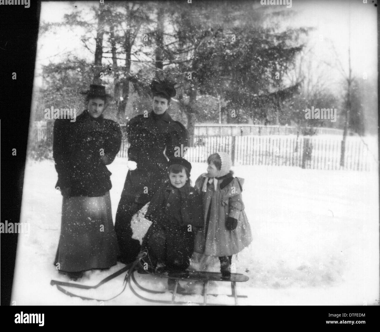 Dieses Foto zeigt zwei Frauen und zwei Kinder auf einem Schlitten und verkörpert die Einfachheit und den Charme des Landlebens. Das Bild spiegelt das gemächliche Tempo und die familienorientierten Aktivitäten wider, die typisch für das ländliche Leben sind, wobei Rodeln als saisonaler Freizeitbeschäftigung gilt. Stockfoto