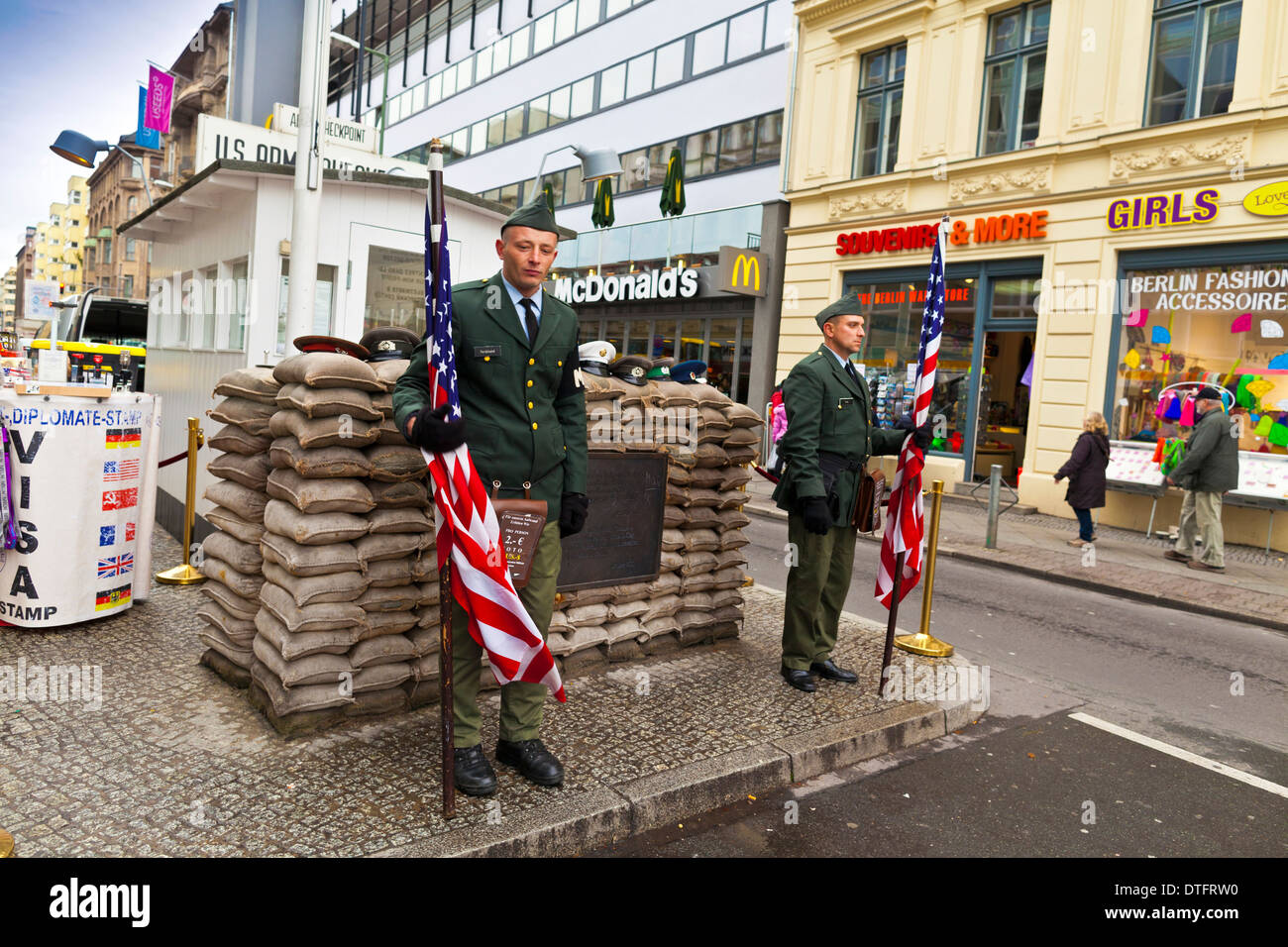 Nicht identifizierte junge Männer gekleidet als amerikanische Soldaten stehen vor dem Checkpoint Charlie in Berlin, Deutschland. Stockfoto