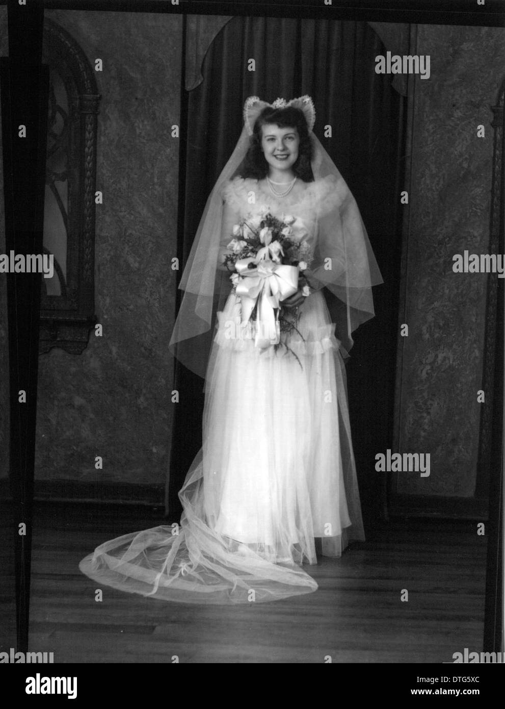 Dieses Vintage-Porträtfoto von Janet Smyser (Fenholt) in ihrem Hochzeitskleid zeigt Mode aus der Mitte des 20. Jahrhunderts und fängt die Eleganz und den Stil der Zeit ein. Stockfoto