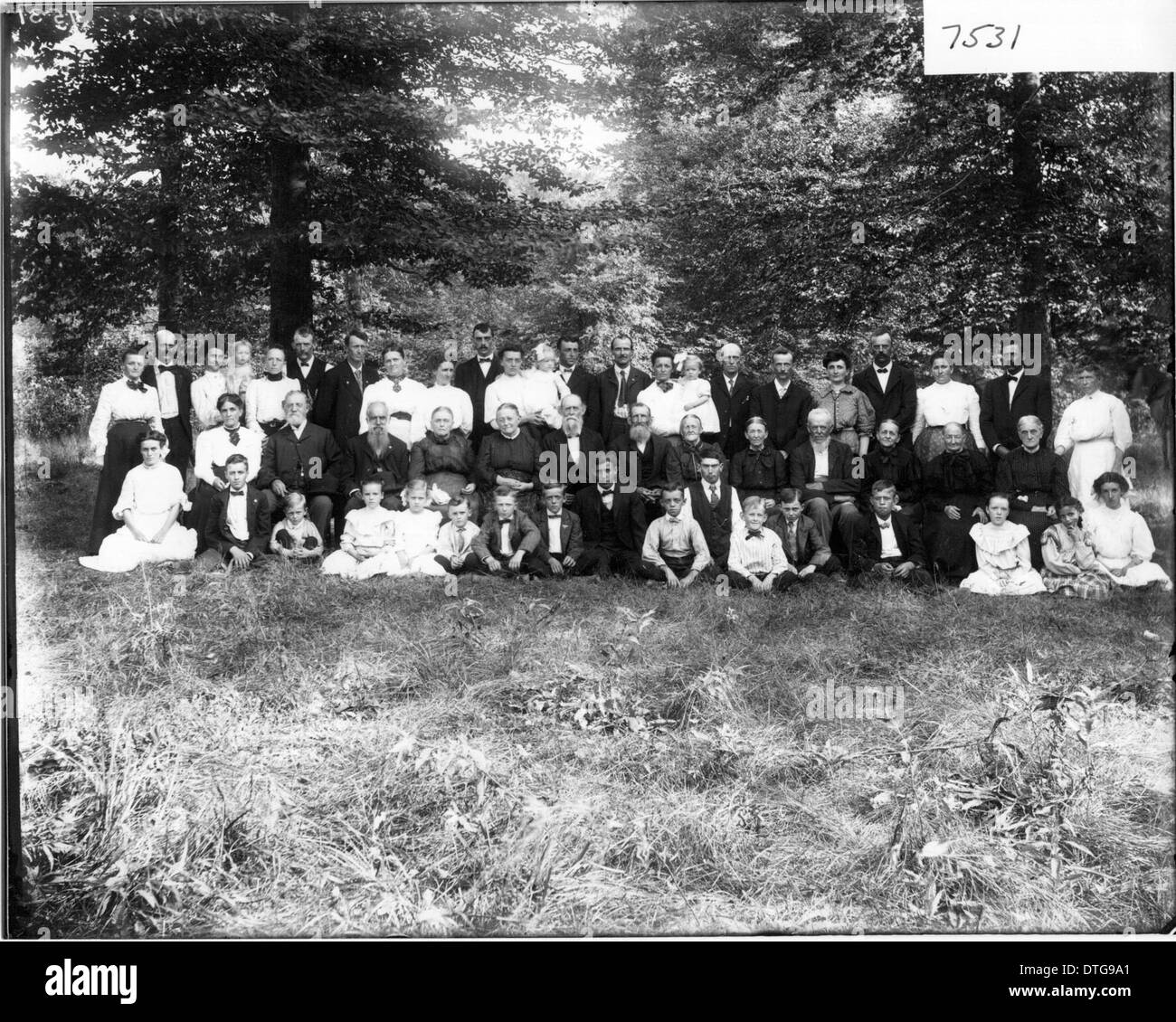 Dieses Gruppenporträt von Thomas Johnson zeigt ein Familientreffen, das sowohl Kinder als auch Erwachsene einfängt. Das historische Bild zeigt das soziale Leben des frühen 20. Jahrhunderts und gibt einen Einblick in die familiären Strukturen dieser Zeit. Stockfoto