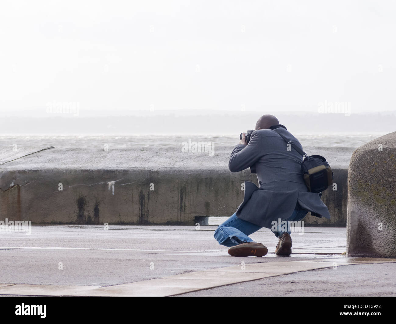 Ein Fotograf fotografiert von Wellen auf Southsea Seafront, England Stockfoto