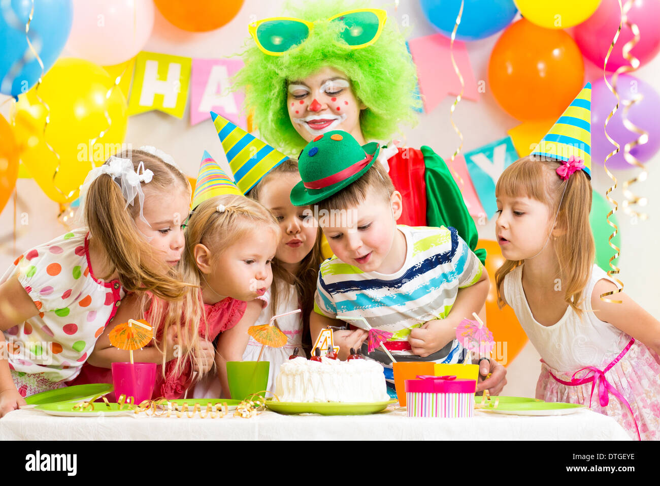 Kinder mit Clown Geburtstagsparty feiern und bläst Kerze auf Kuchen Stockfoto