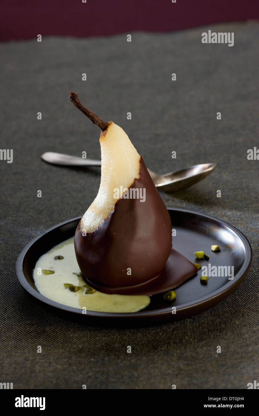 Birne in Schokolade, Pudding und Pistazien beschichtet Stockfoto