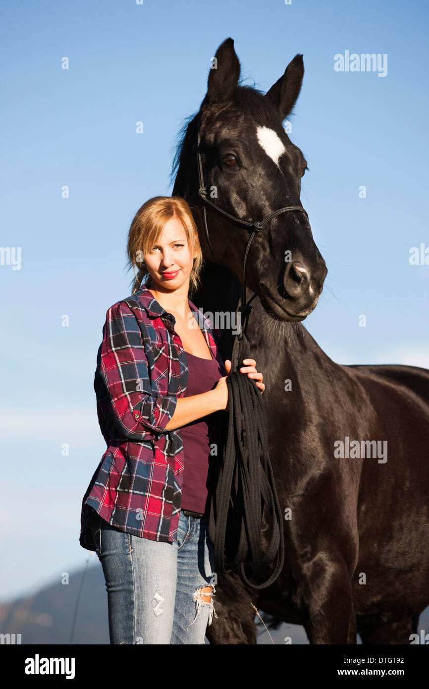 Eine junge Frau mit einem schwarzen Hannoveraner Pferd Nord Tirol, Österreich Stockfoto