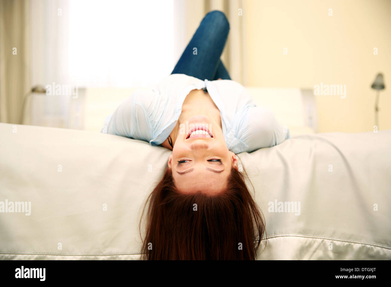 Lustige lächelnde Frau liegend auf dem Bett zu Hause Stockfoto