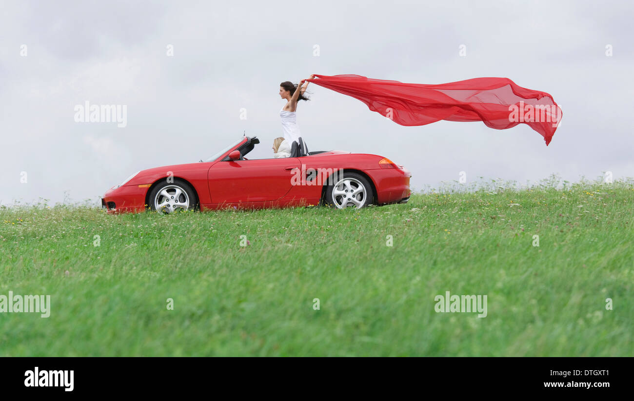 Frau in einem Cabrio Vermietung ein rotes Tuch flattern im Wind, Deutschland Stockfoto
