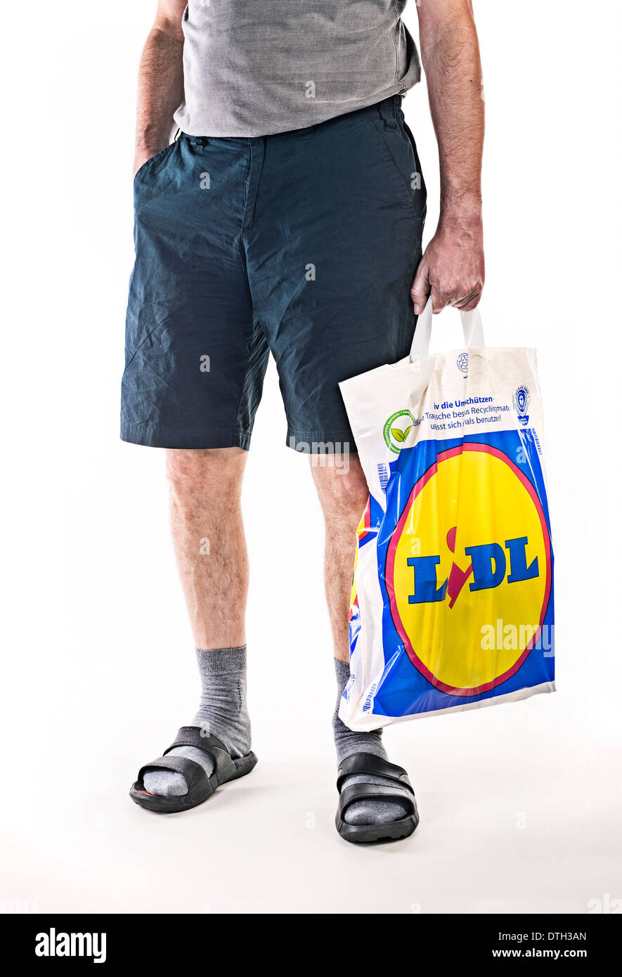 Unterkörper von einem Mann mit kurzen Hosen, mit einer Plastiktüte Lebensmittel-Discounters Lidl. Stockfoto