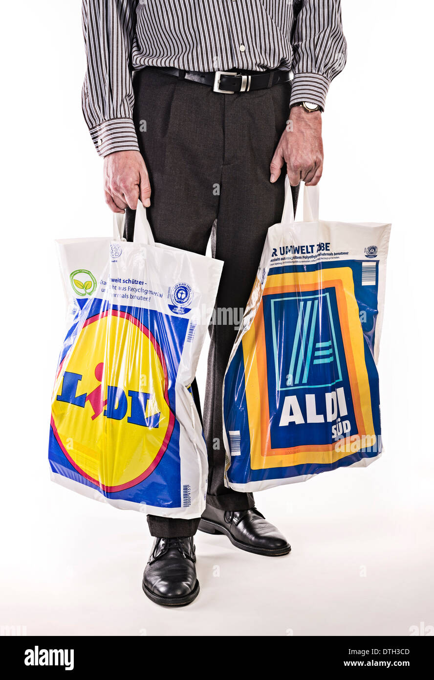 Unterkörper von einem Mann in einem Anzug mit Plastiktüten der Discounter Lidl und Aldi. Stockfoto