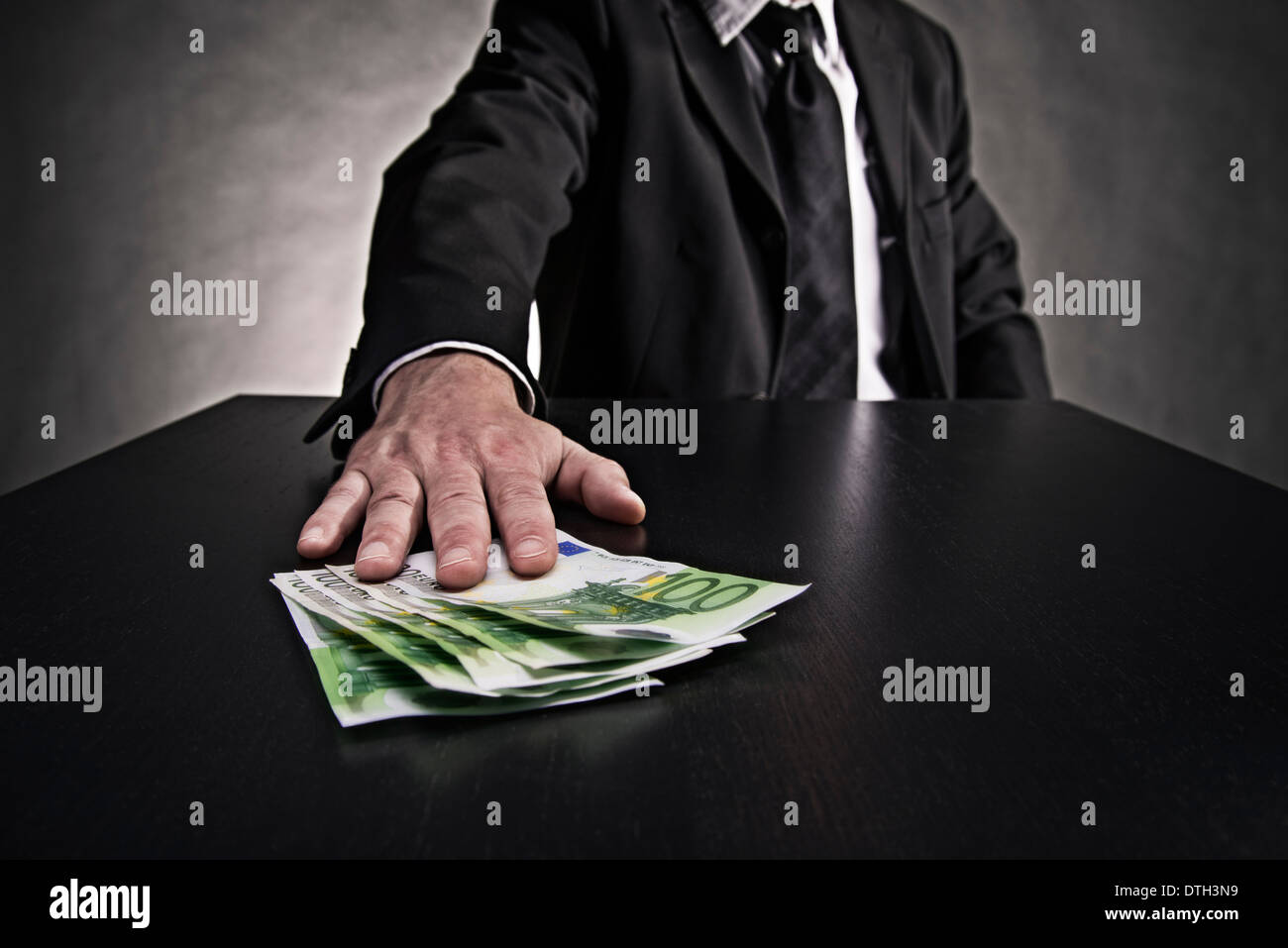 Thema Bestechung: Hand schiebt Euro-Scheine auf den Tisch. Stockfoto
