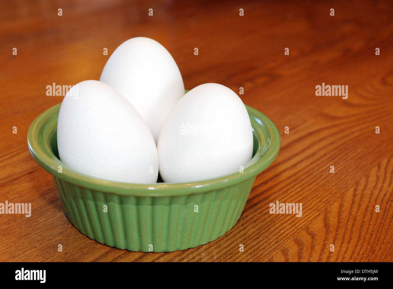 Drei Eiern in einer grünen Keramik Schüssel über Holztisch, Heim- oder Kochen Konzept Stockfoto