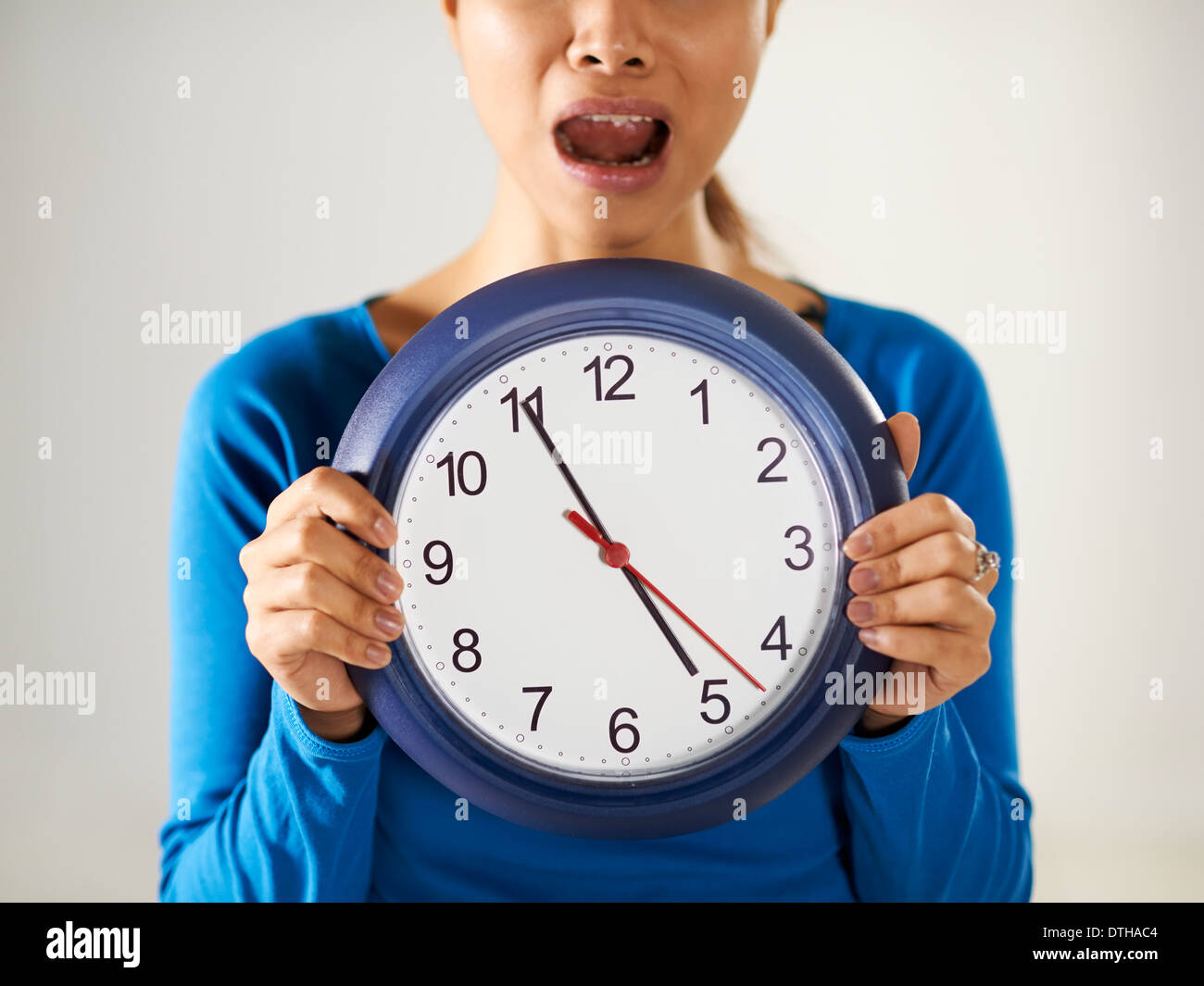 Porträt von asiatischen Geschäftsfrau hält große blaue Armbanduhr und Blick in die Kamera mit Sorge Ausdruck Stockfoto